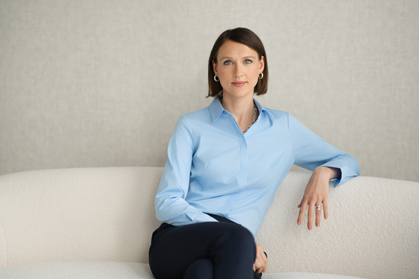 Steuerberaterin Marleen Meißner sitzt auf einem beigen Sofa und lächelt in die Kamera